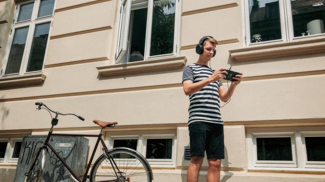 Gamer outdoors wearing Arctis 3 - Black gaming headset, connected to and playing a Nintendo Switch game console